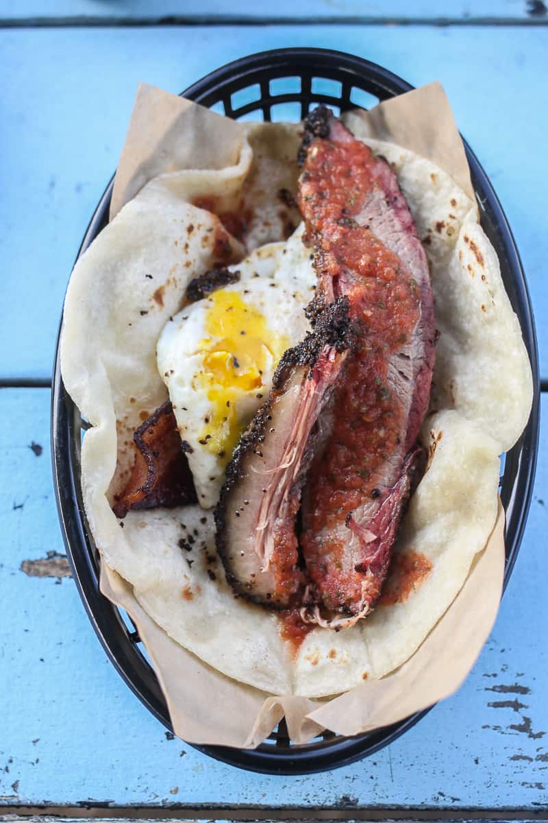 Best Austin Restaurants: Valentina’s Tex Mex's breakfast tacos made with a homemade flour tortilla, fried egg, potatoes, bacon, serrano salsa, and a slice of their marvelous brisket