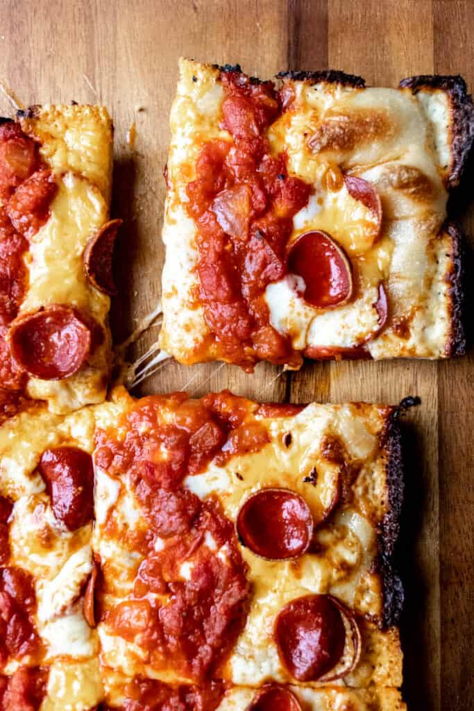 Detroit-style pizza slice being pulled away from pizza.