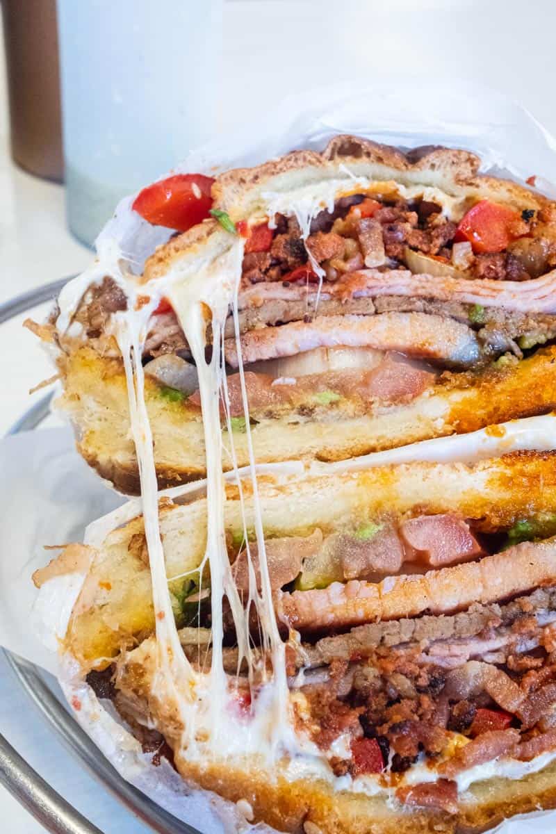Sandwich loaded with beefsteak, thinly sliced ham, crispy chorizo, thick-cut bacon, AND a porkchop, plus peppers, onions, and Oaxaca cheese