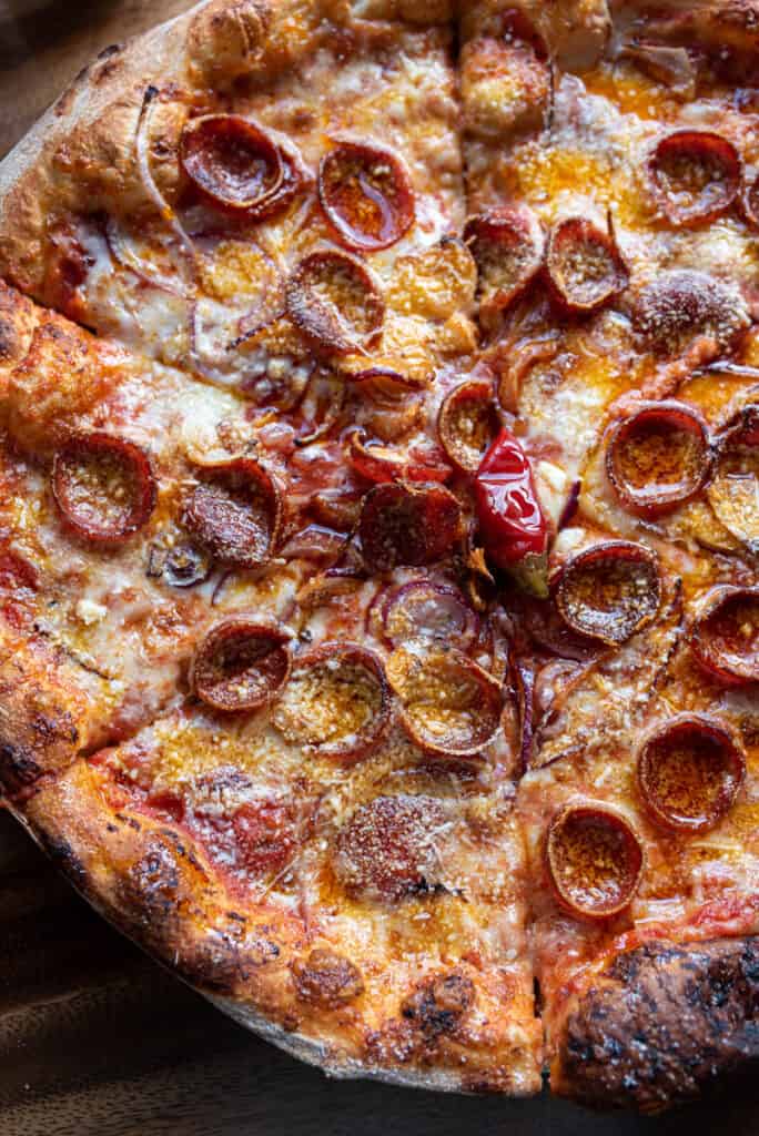 a spicy pepperoni pizza paired with chili peppers, garlic, and red onions by Pink Onion
