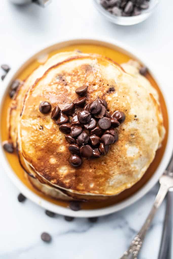 Stack of banana bread pancakes with chocolate chips on top.