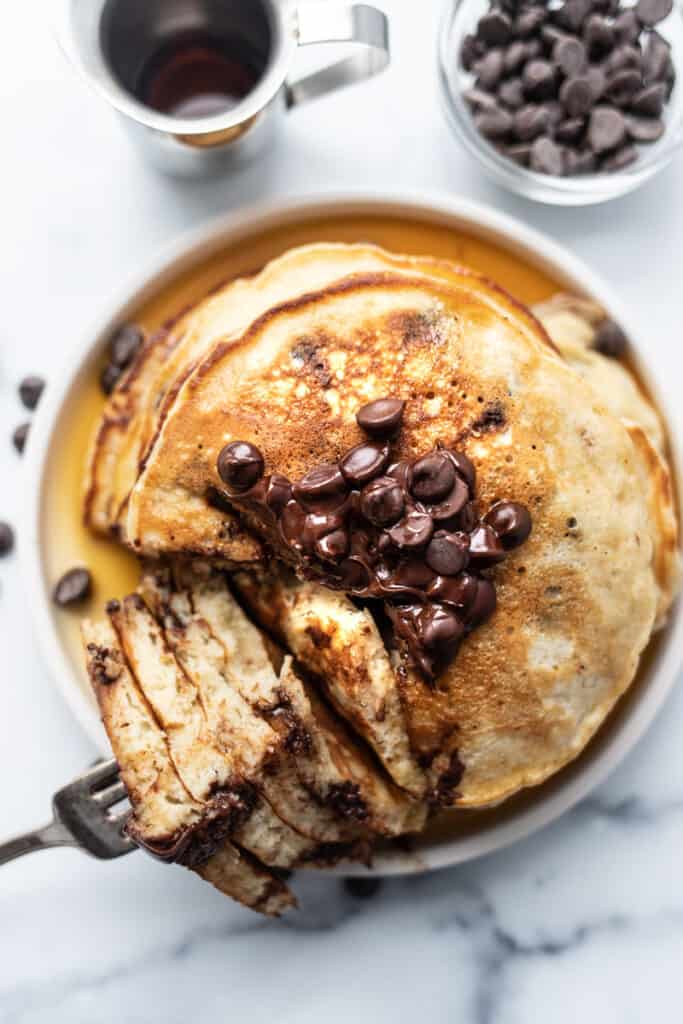 Stack of banana bread pancakes with chocolate chips on top, cut into.