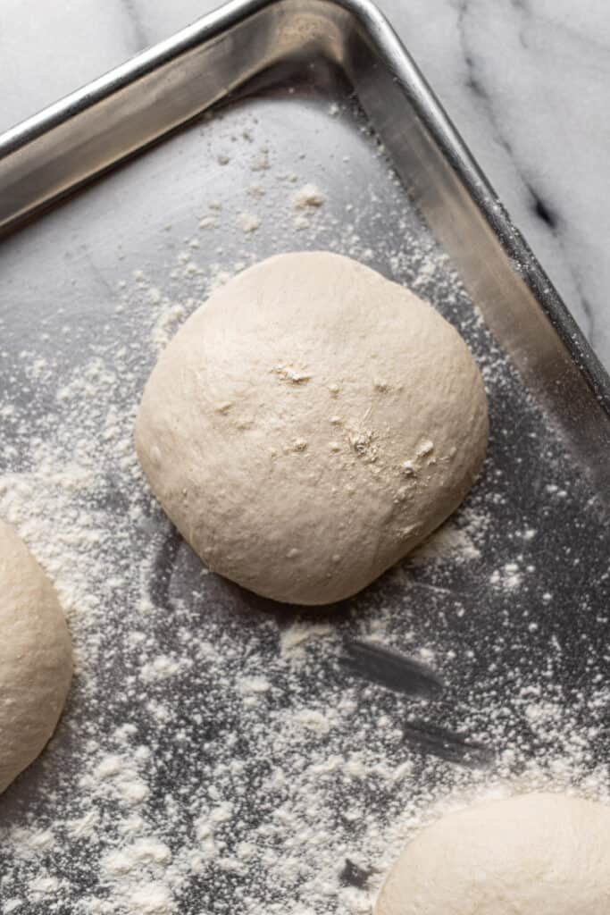 Sourdough pizza dough on cookie sheet with flour. 
