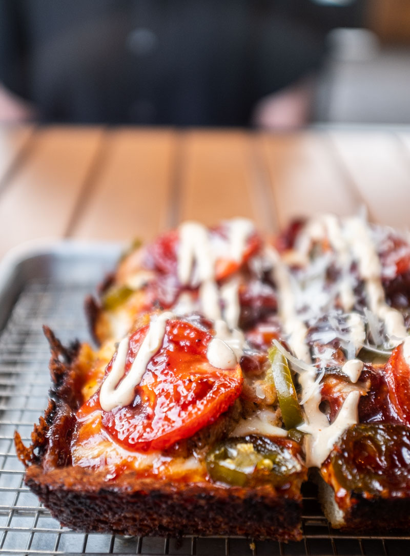 Sweet Salty Pig by Brick's Corner, comes with tender BBQ pork shoulder, crispy bacon, thick slices of fresh tomatoes, caramelized onions, and pickled jalapeno chips with a homemade ranch dressing drizzled over the top. 