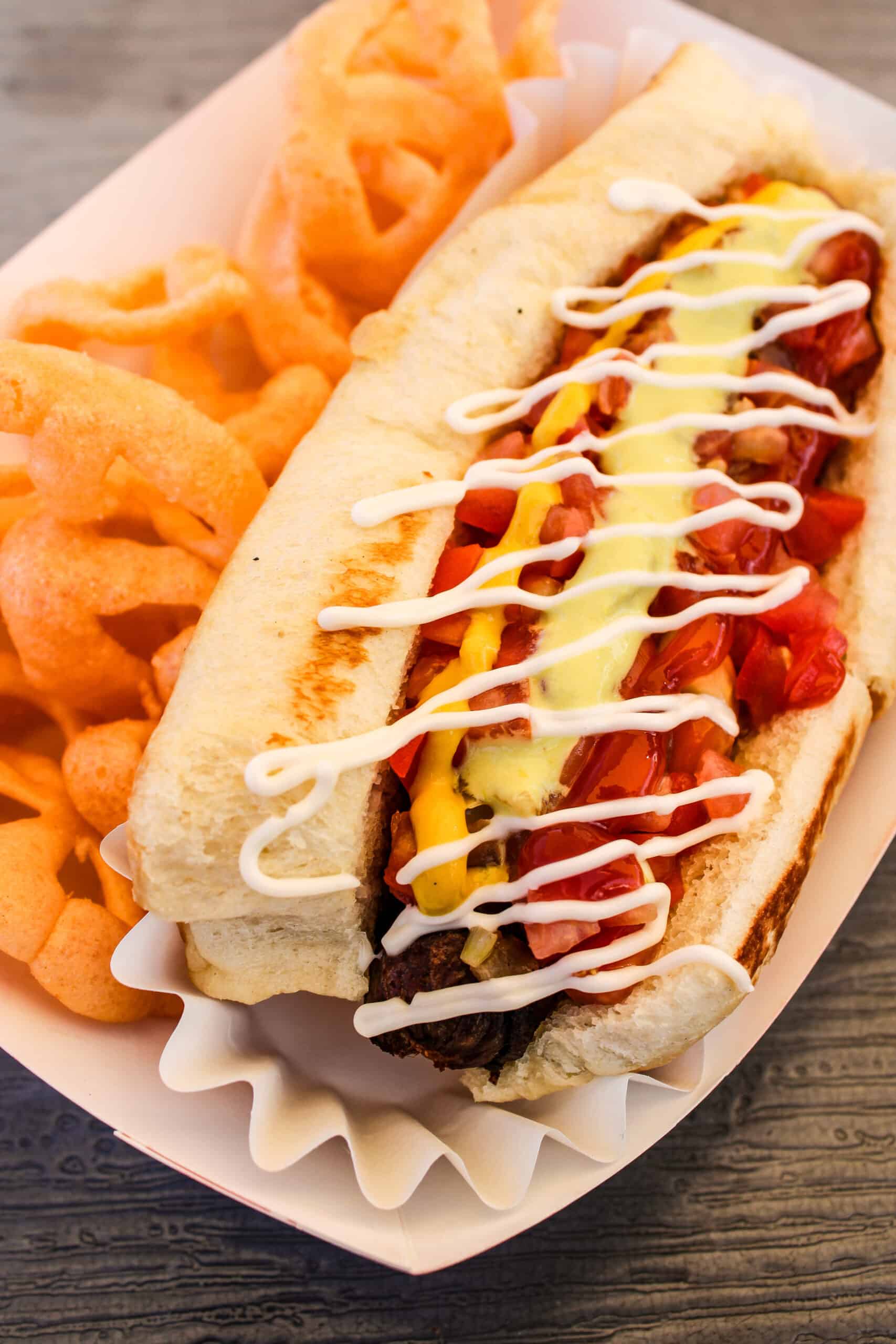 Sonoran dog- a bacon-wrapped hot dog, topped with jalapeno sauce, mayo, ketchup, mustard, grilled onions, tomatoes, pinto beans, and cheese by Nana Sonoran