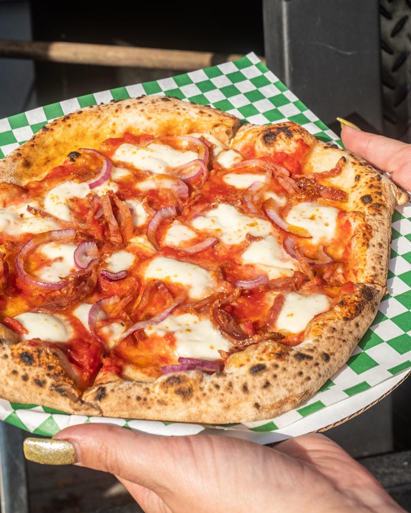 Diavola by Pizzeria Tasso, a tomato based pizza with fresh mozzarella, salami, red onions, parmesan, and their spicy signature oil on top of a classic woodfired crust