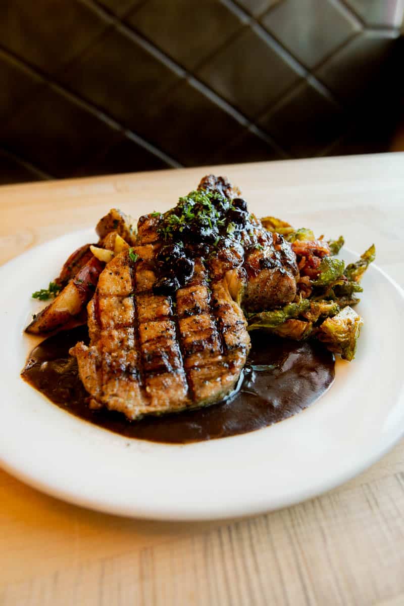 pork chop topped with a sweet blueberry compote and served with crispy brussel sprouts roasted with bacon from Brick 29 Bistro