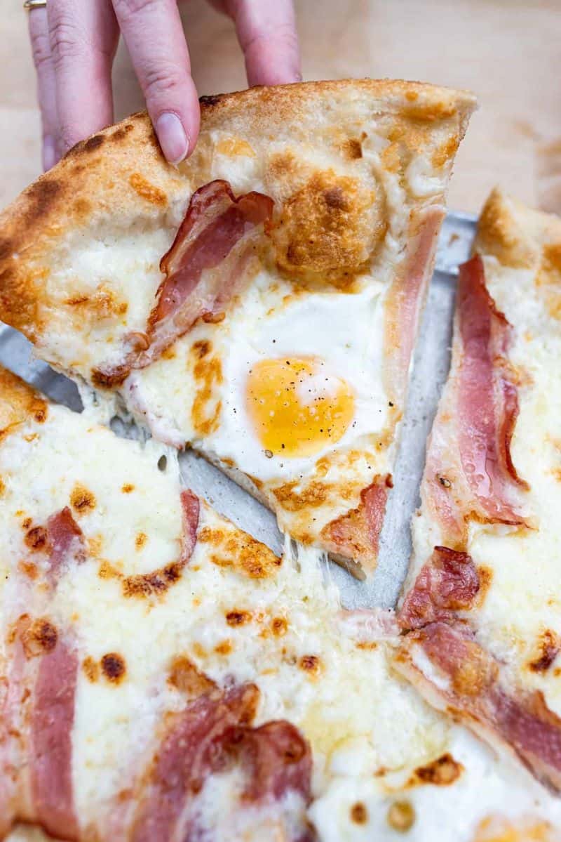 carbonara pizza- topped with a cream-based sauce, pancetta, a gooey blend of cheeses, and two sunnyside-up eggs by Delarosa