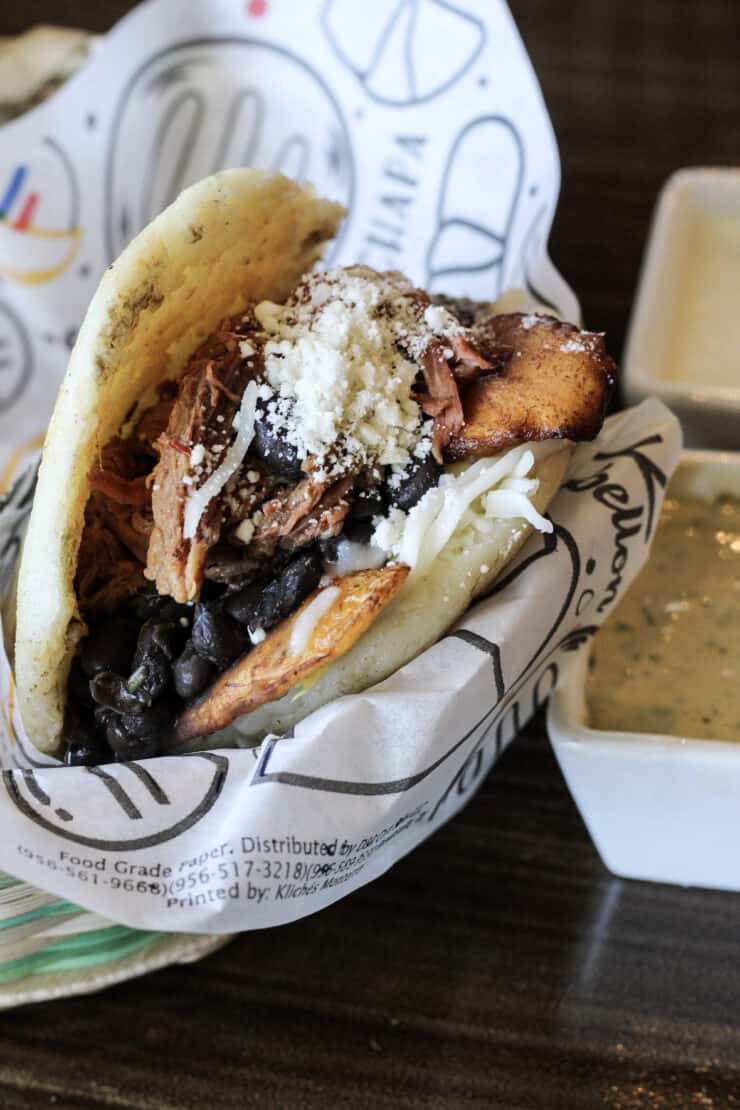 pabellon arepa filled with tender, shredded beef, fried plantains, black beans, and cheese by Arempas