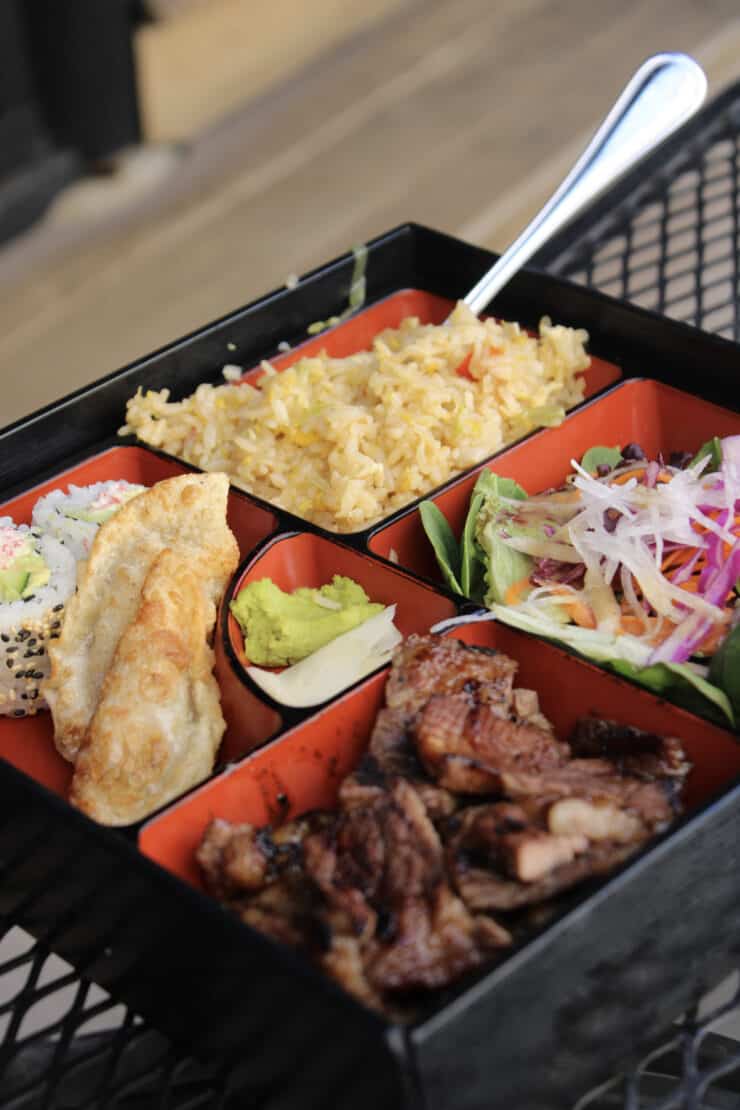 Sapa's short rib bento box featuring fried rice, grilled boneless pieces short ribs, house salad, pork dumplings, and a classic California roll