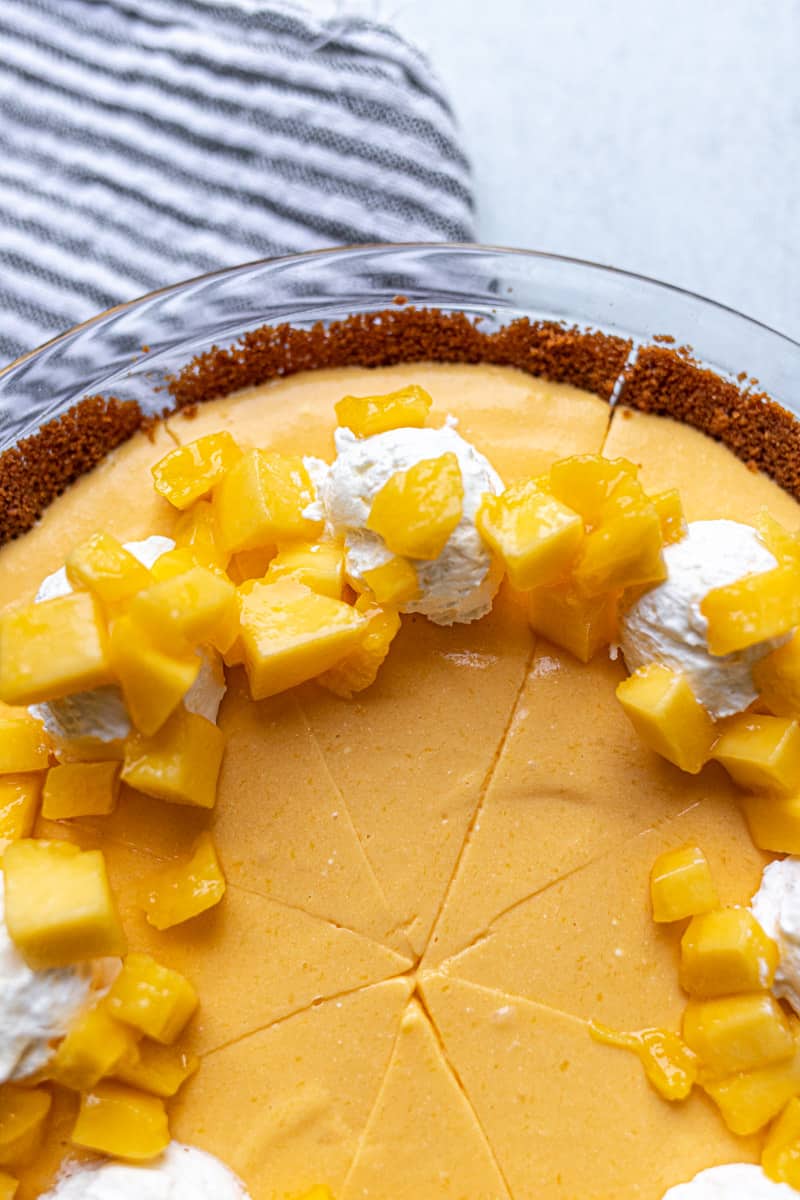 close up view of mango pie with whipped cream and mango pieces 